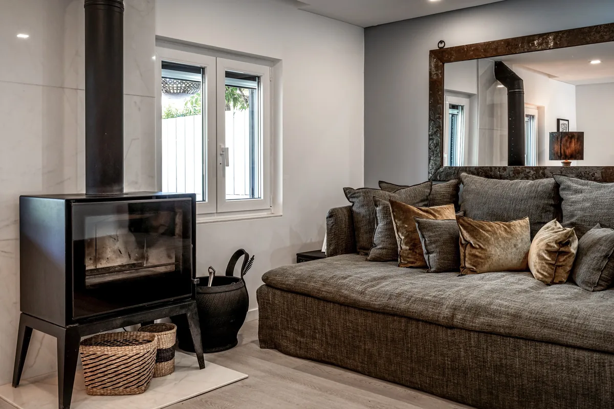Living room with dark sectional sofa and wood-burning stove at Comporta Village House